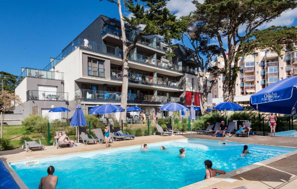 uma piscina em frente a um hotel com pessoas nele em Résidence Prestige Odalys De La Plage em Pornichet