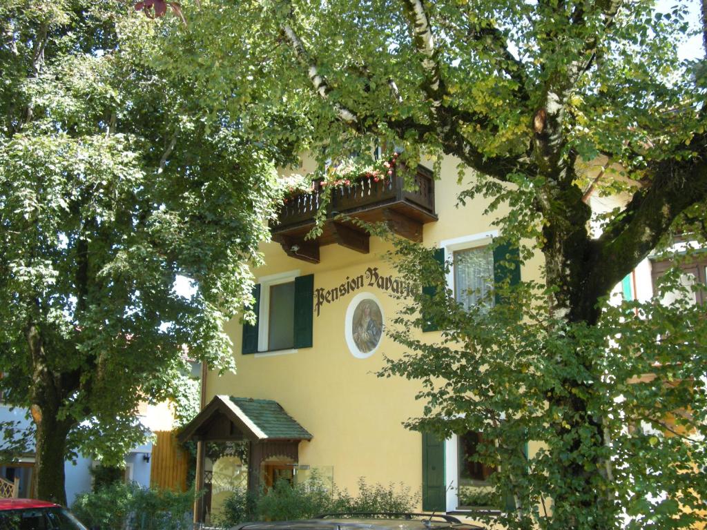 ein gelbes Gebäude mit einer Uhr auf der Seite in der Unterkunft Pension Bavaria in Mittenwald