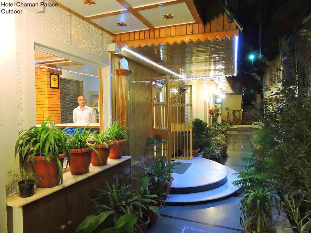 um homem parado num restaurante com vasos de plantas em Hotel Chaman Palace em Shimla