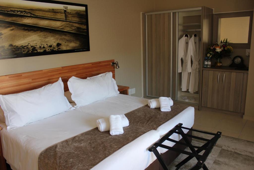 1 dormitorio con 1 cama blanca grande y toallas. en Prost Hotel Swakopmund Namibia en Swakopmund