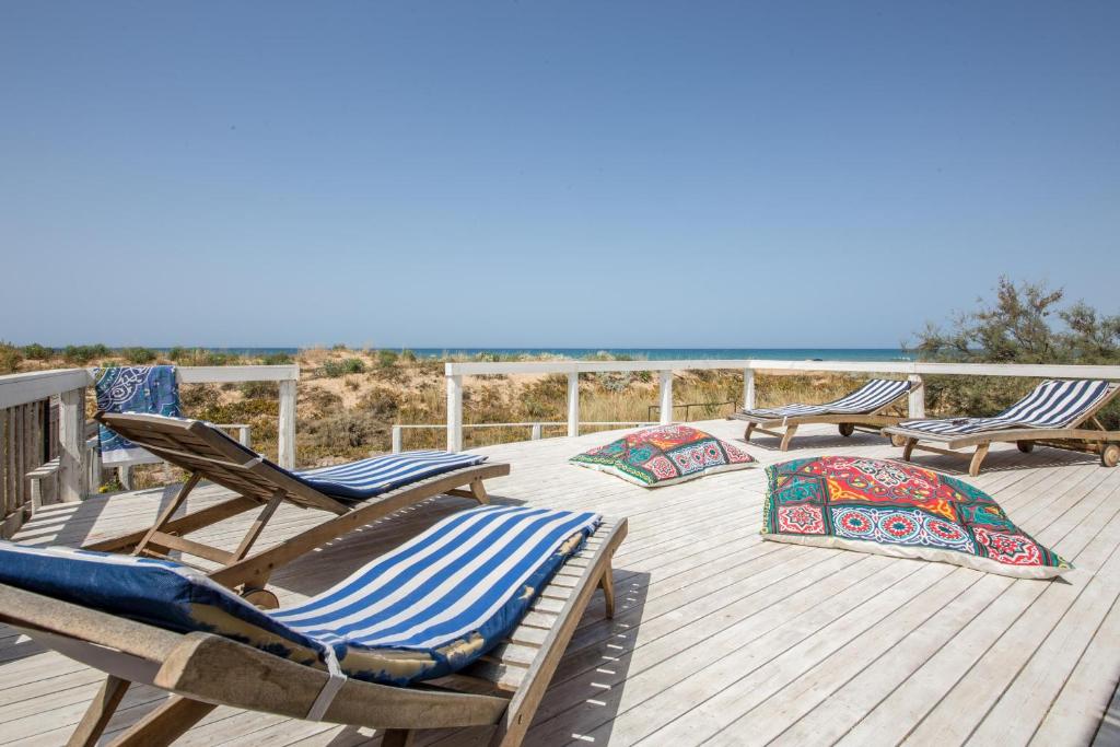 a deck with chaise lounges and chairs on the beach at Villa Unica Terrazzo Sul Mare in Donnalucata