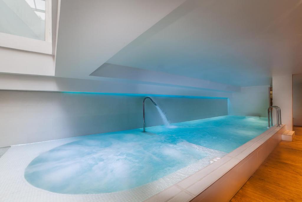 a hot tub with blue water in a room at Hôtel Montaigne & Spa in Cannes