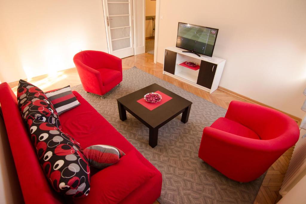 een woonkamer met een rode bank en 2 stoelen bij Dositej 5 Apartment in Belgrado