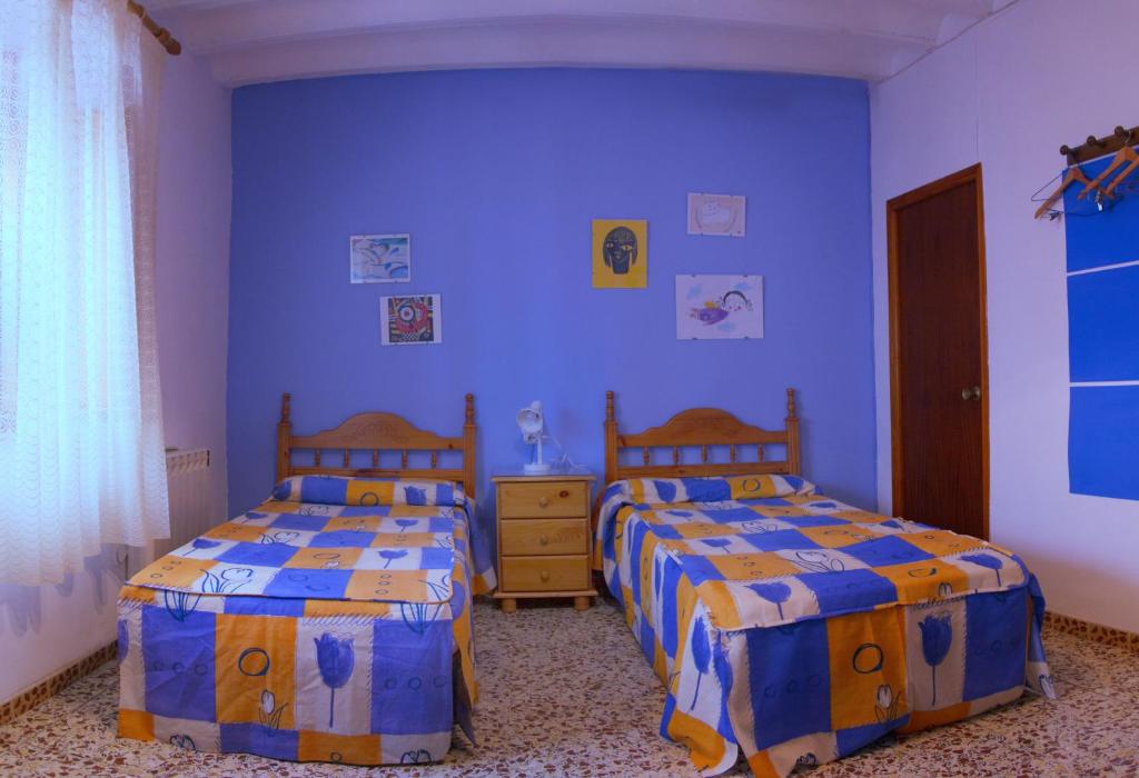 two beds in a bedroom with blue walls at La casa de la acequia in Serón