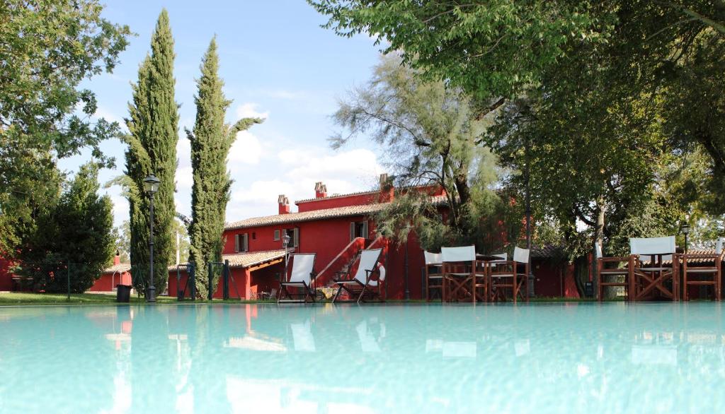 a swimming pool with chairs and a red building at Residenza Torre Acquatino in Spello