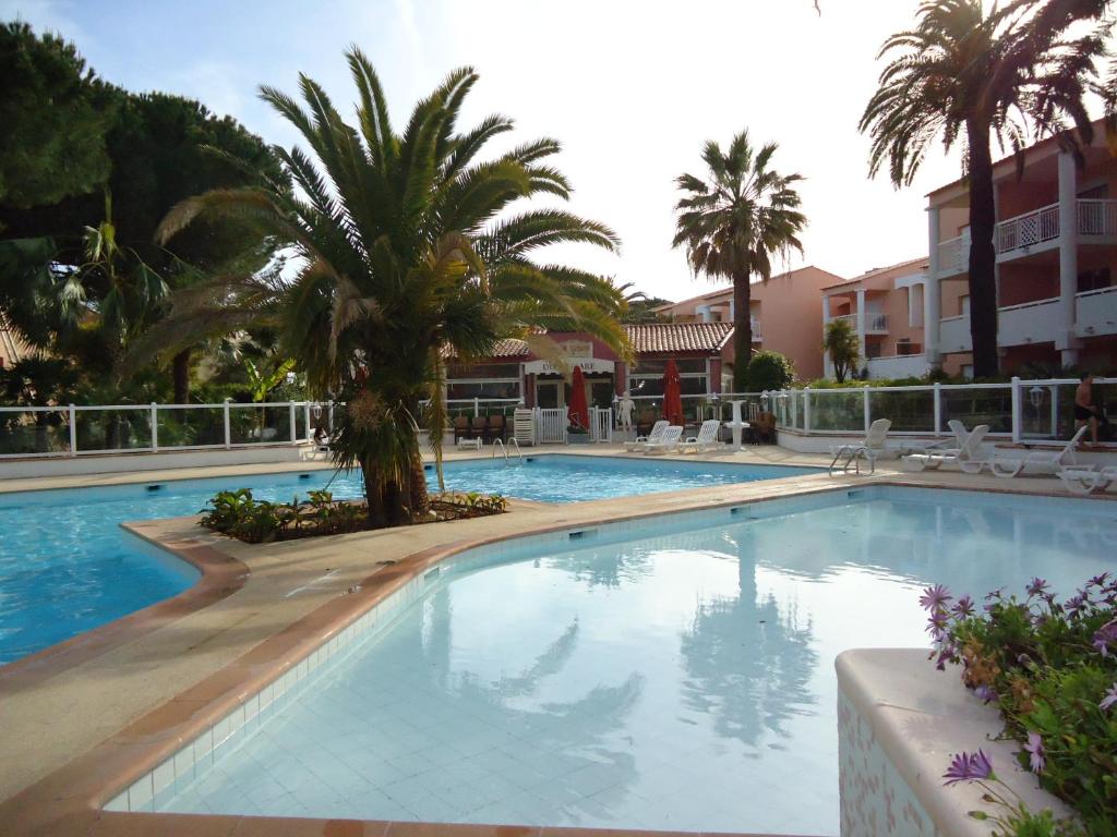 une grande piscine avec des palmiers et des bâtiments dans l'établissement App T2 cozy Proche de la Mer, au Golfe-Juan