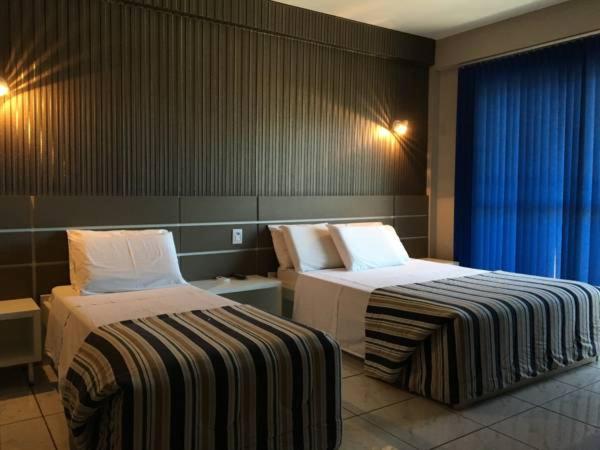 ein Hotelzimmer mit 2 Betten und einem Fenster in der Unterkunft Hotel Nossa Casa in Ijuí