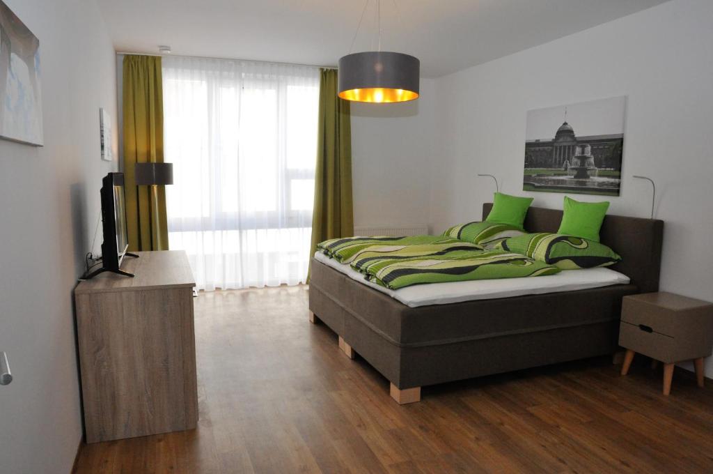 a bedroom with a bed with green pillows and a television at Apartment an den Quellen in Wiesbaden