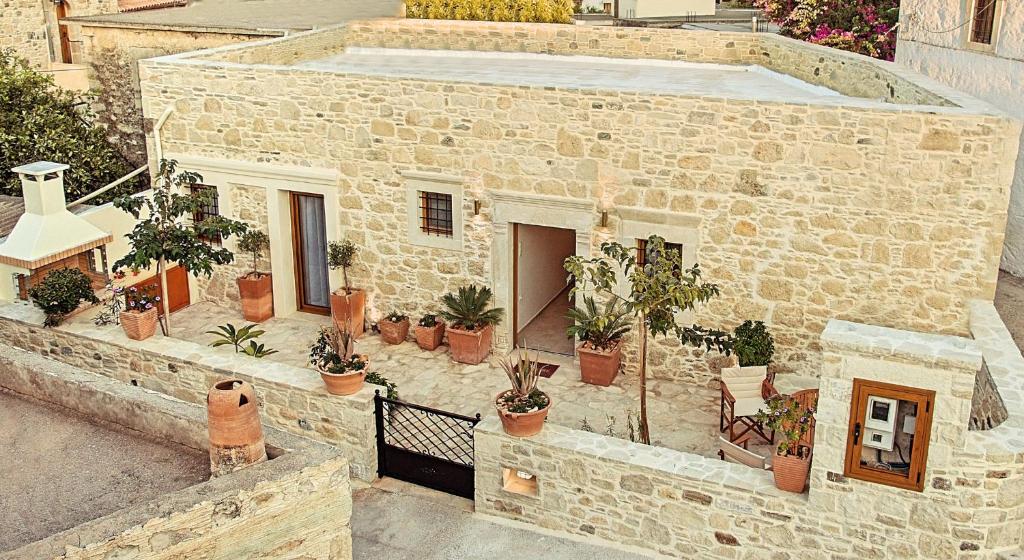 un bâtiment en pierre avec une bande de plantes en pot dans l'établissement Villa Kapela, à Sívas
