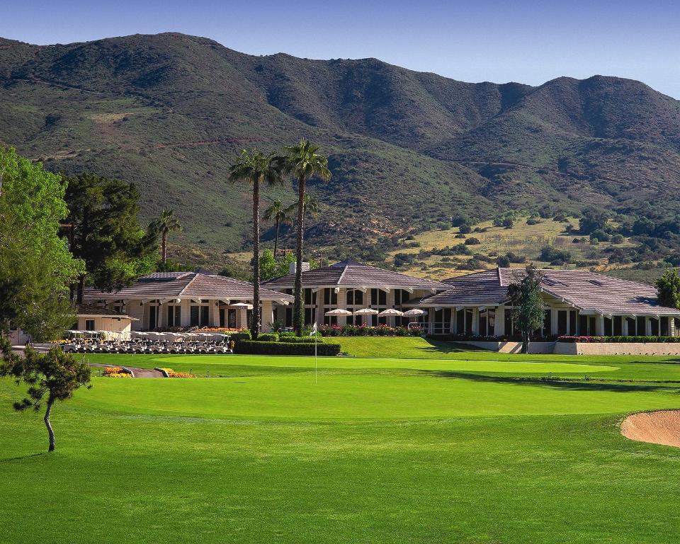 a golf course with a house and mountains in the background at Pala Mesa Resort in Fallbrook