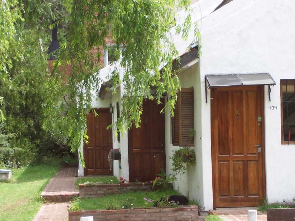 a white house with wooden doors and a tree at Duplex Valeria del Mar in Valeria del Mar