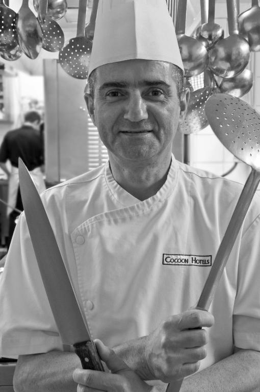 a man in a chefs hat holding two large knives at Cocoon Hotel Belair in Bourscheid
