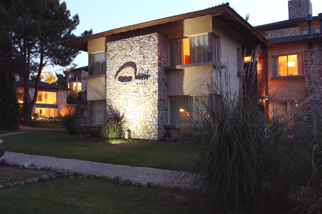 a house with a stone facade with lights on at Altué Apart Hotel in Mar de las Pampas