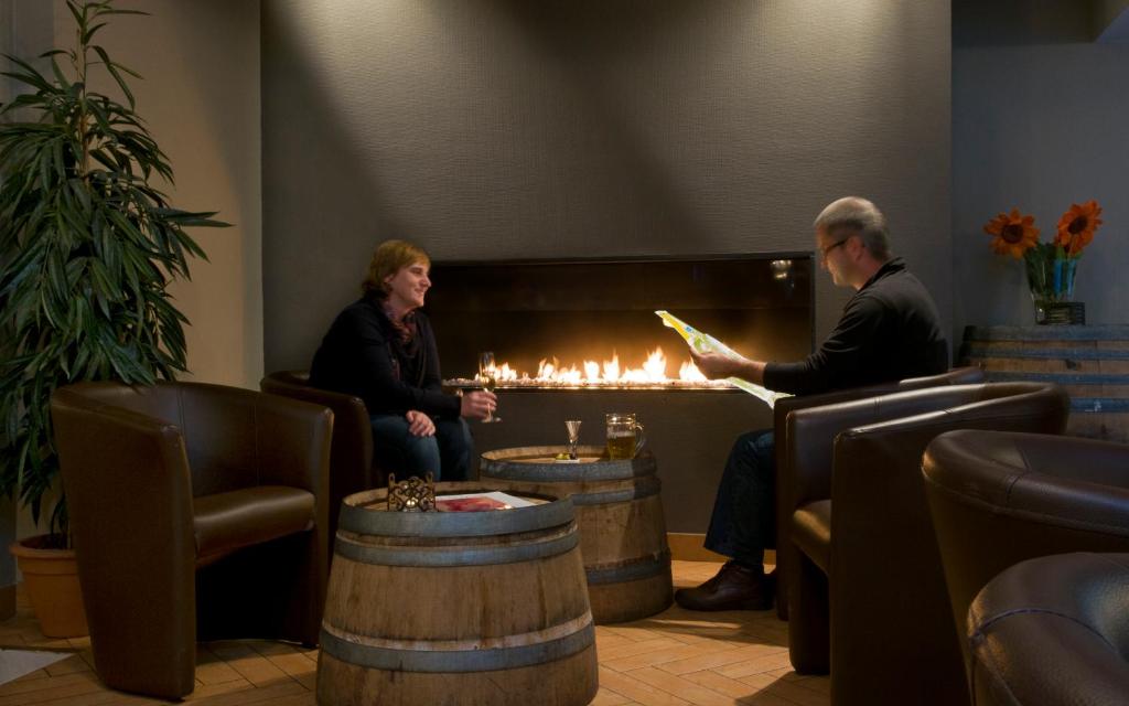 two people sitting in a room with a fireplace at Cocoon Hotel Belair in Bourscheid