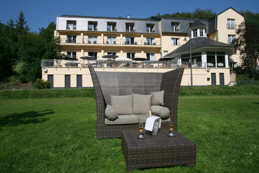 a wicker chair sitting in the grass in front of a building at Cocoon Hotel Belair in Bourscheid