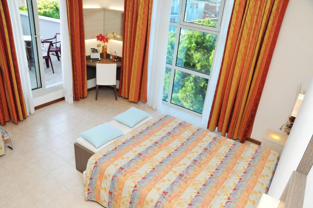a bedroom with a bed and a table and windows at Hotel Venezia in Caorle