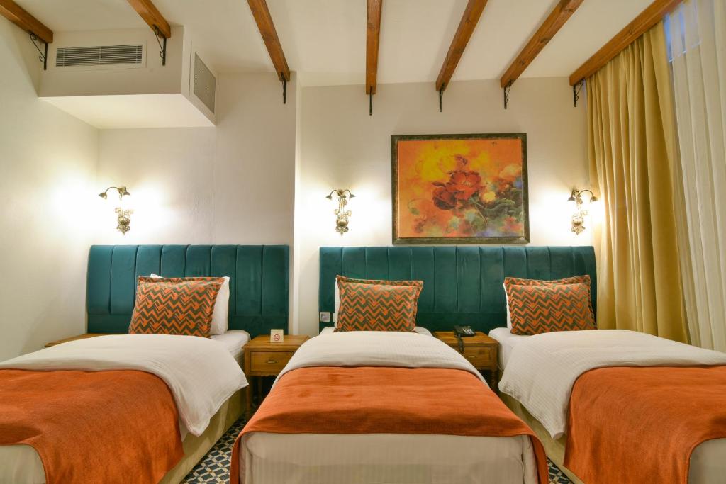 a room with three beds and a painting on the wall at Istanbul Life Hotel in Istanbul