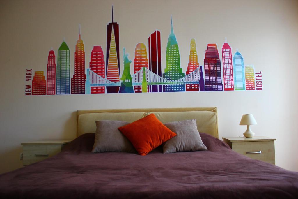 a bedroom with a bed with a painting of buildings at New York Hostel in Lviv