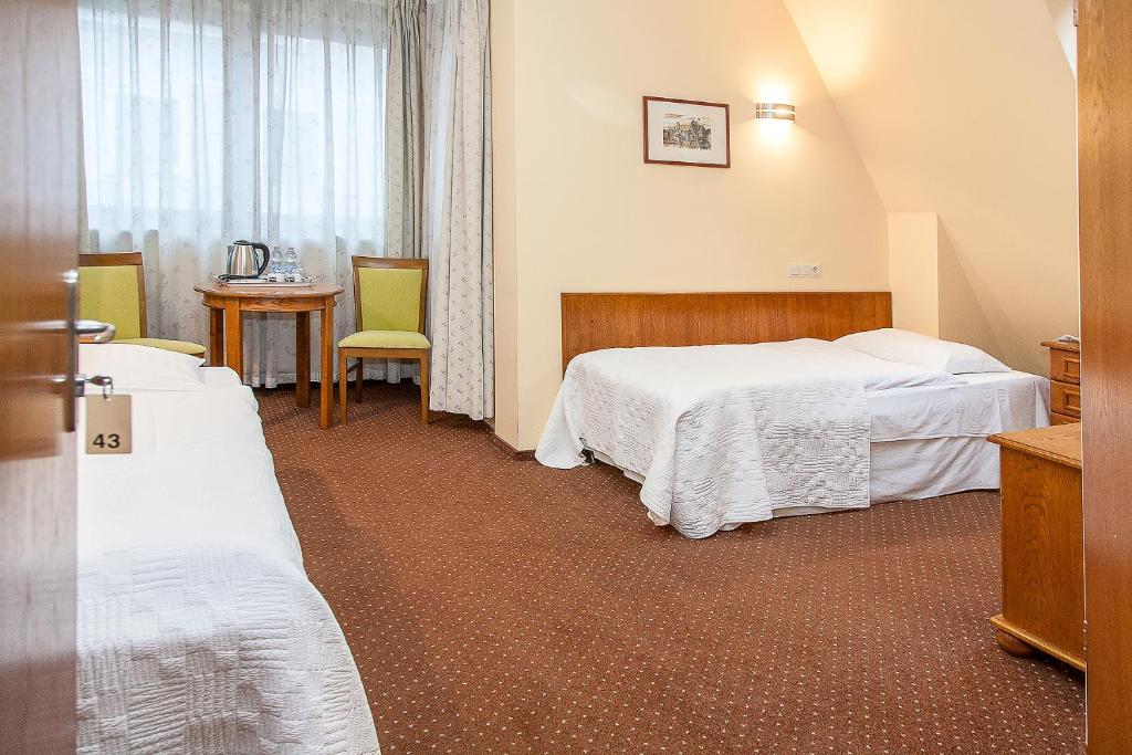 a hotel room with two beds and a table at Willa Biala Lilia Old Town in Gdańsk