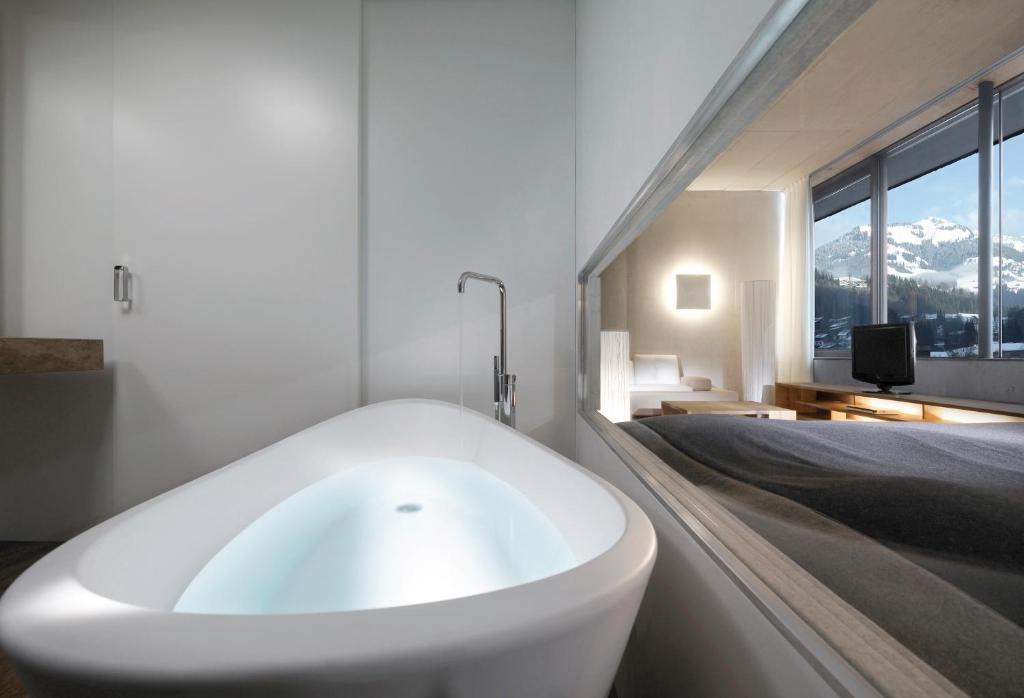 a bathroom with a white bath tub next to a bed at Schwarzer Adler Kitzbühel - Adults Only in Kitzbühel