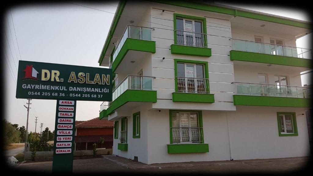 un edificio con balcones verdes y una señal frente a él en Dr Aslan Apart Hotel, en Esenboga