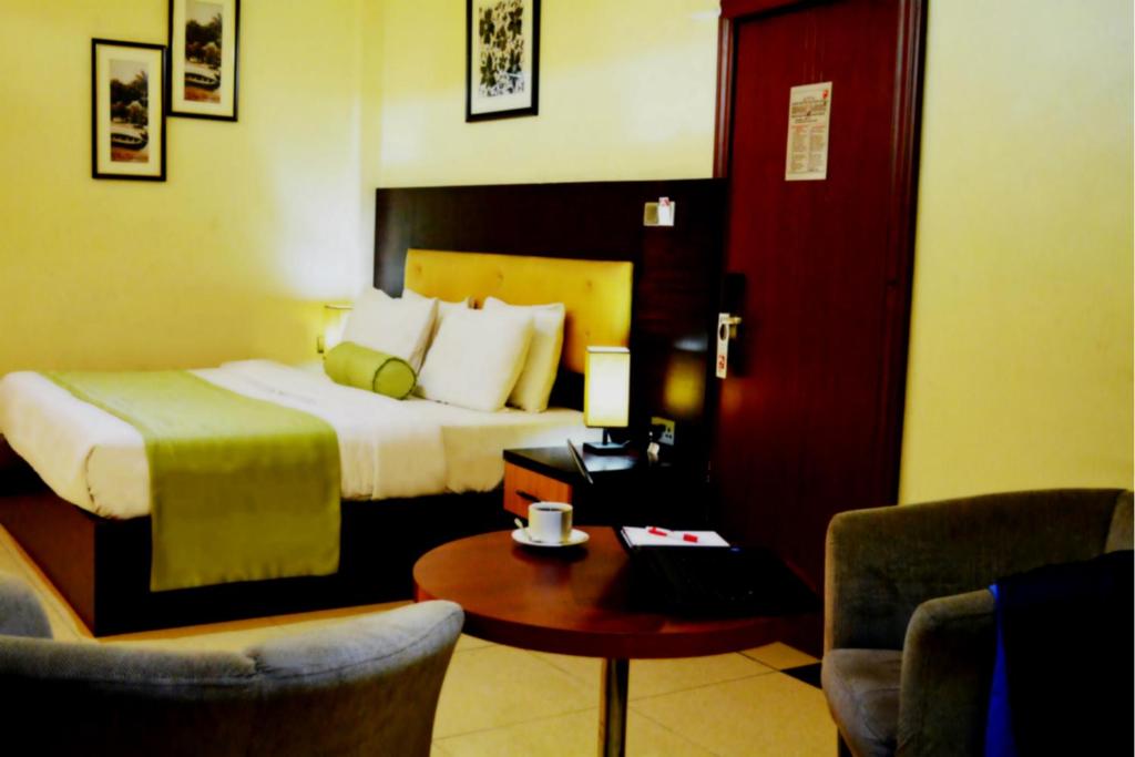 a hotel room with a bed and a table and chairs at Sweet Spirit Hotel and Suites Danag - Port Harcourt in Port Harcourt