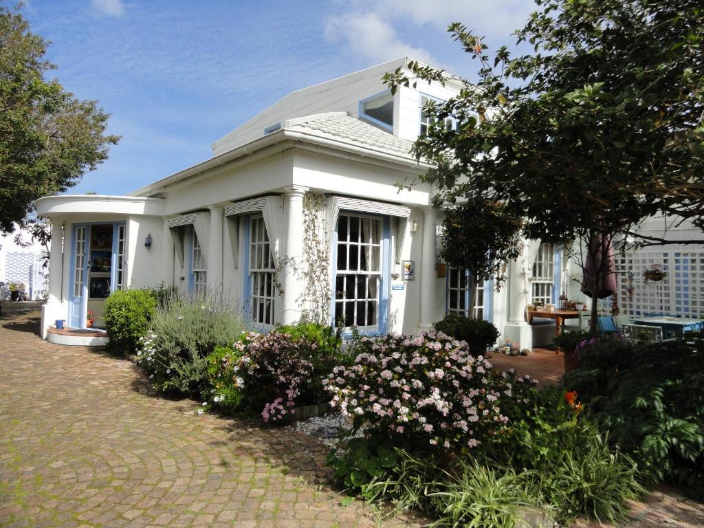 een wit huis met bloemen ervoor bij Eastbury Cottage in Hermanus