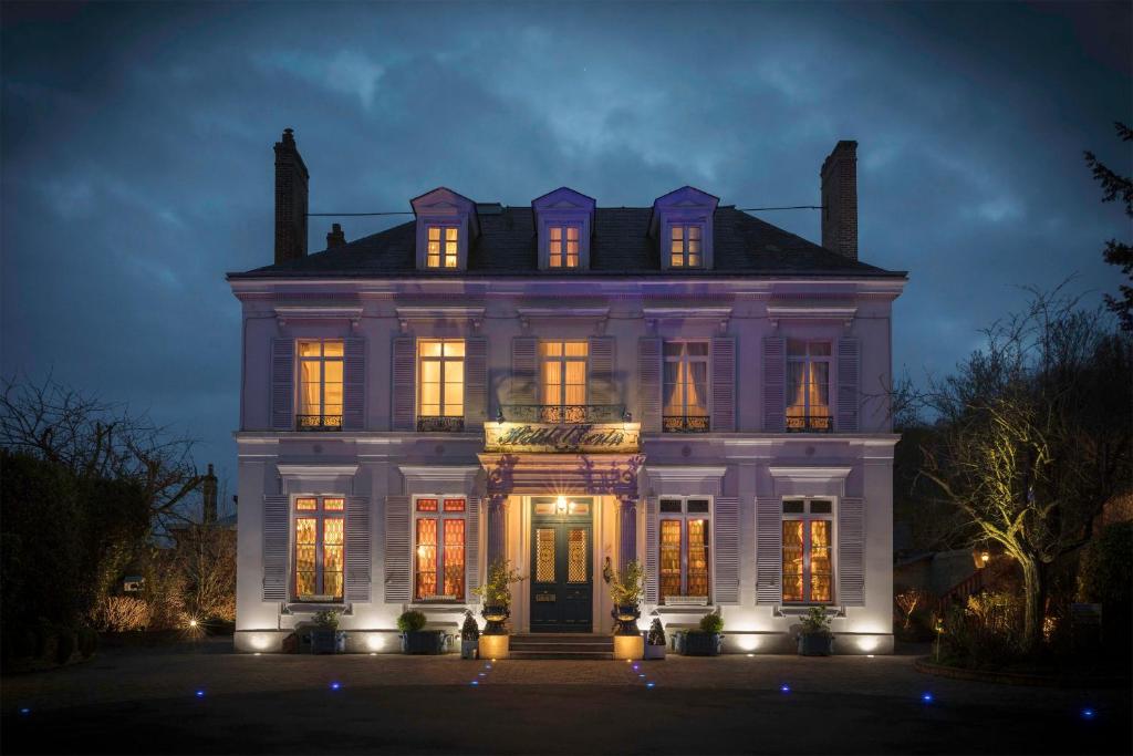 una gran casa blanca con sus luces encendidas en Hôtel L'Ecrin en Honfleur