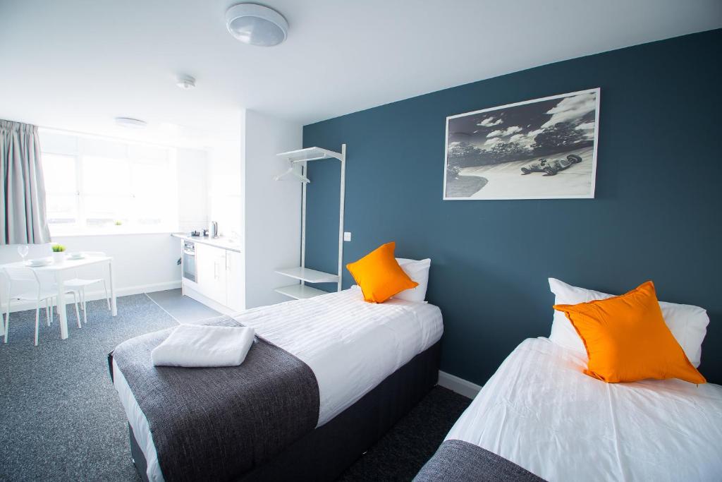 2 camas en una habitación con paredes azules y almohadas de color naranja en Fox Street Studios en Liverpool