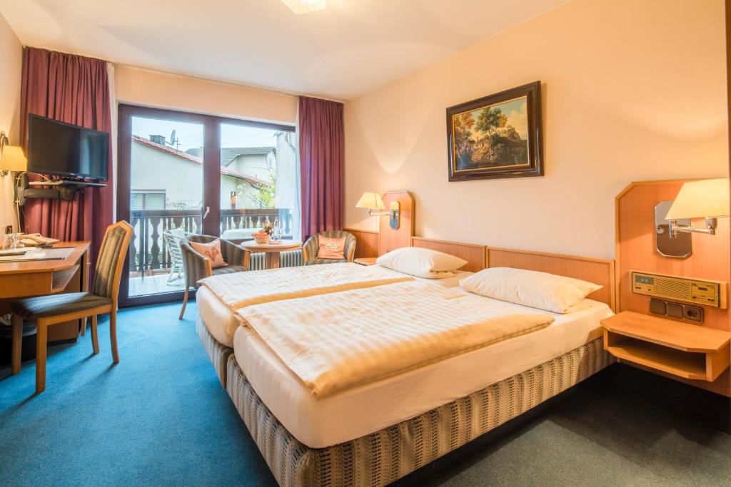 ein Hotelzimmer mit einem großen Bett und einem Schreibtisch in der Unterkunft Hotel-Barbarossa-Garni bei Hanau in Rodenbach