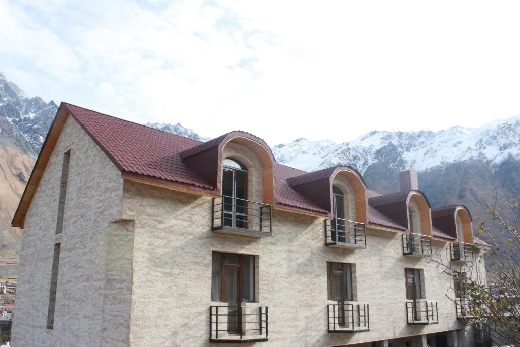 un edificio con finestre e tetto con montagne sullo sfondo di Hotel Gergeti a Kazbegi