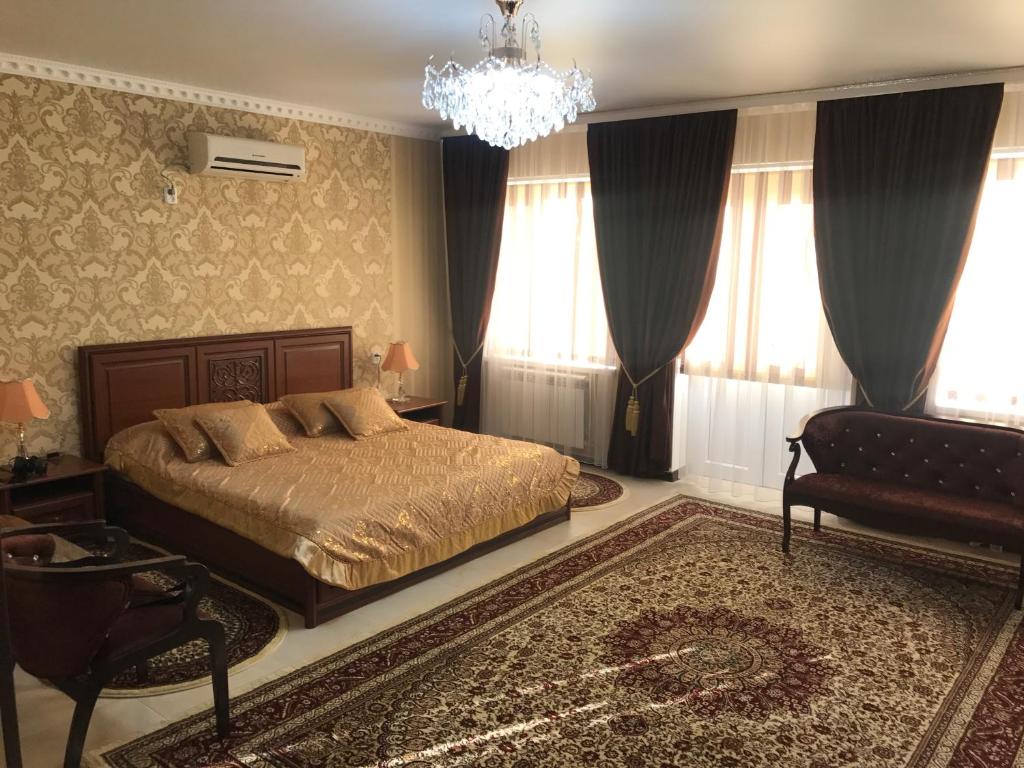 1 dormitorio con cama y lámpara de araña en Gostinitsa Grand, en Kyzylorda