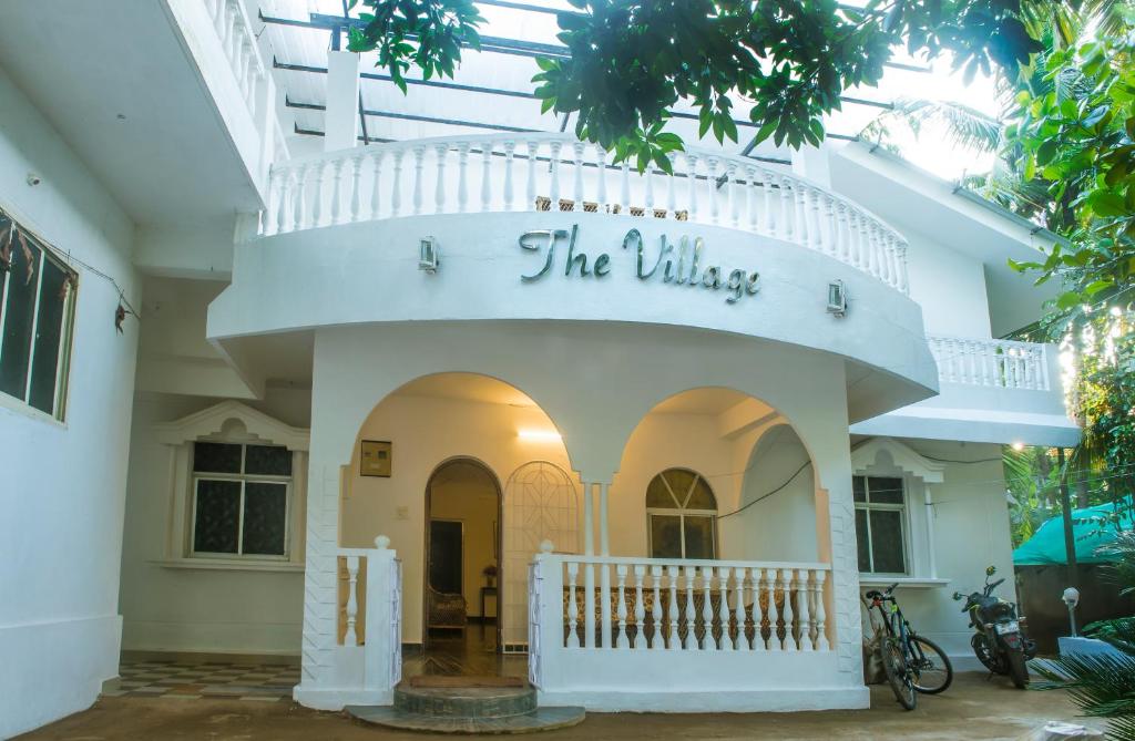 a white building with a sign that reads the village at The Village Resort Palolem in Palolem