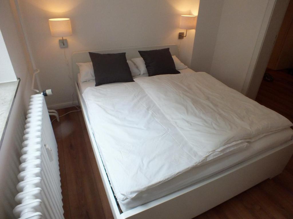 Una cama con sábanas blancas y almohadas negras. en Apartment am Blücher, en Kiel