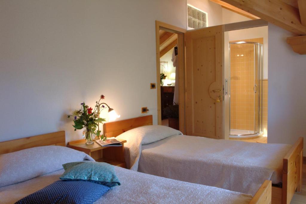 a bedroom with two beds and a door to a bathroom at B&B Casa Riz in Castello di Fiemme