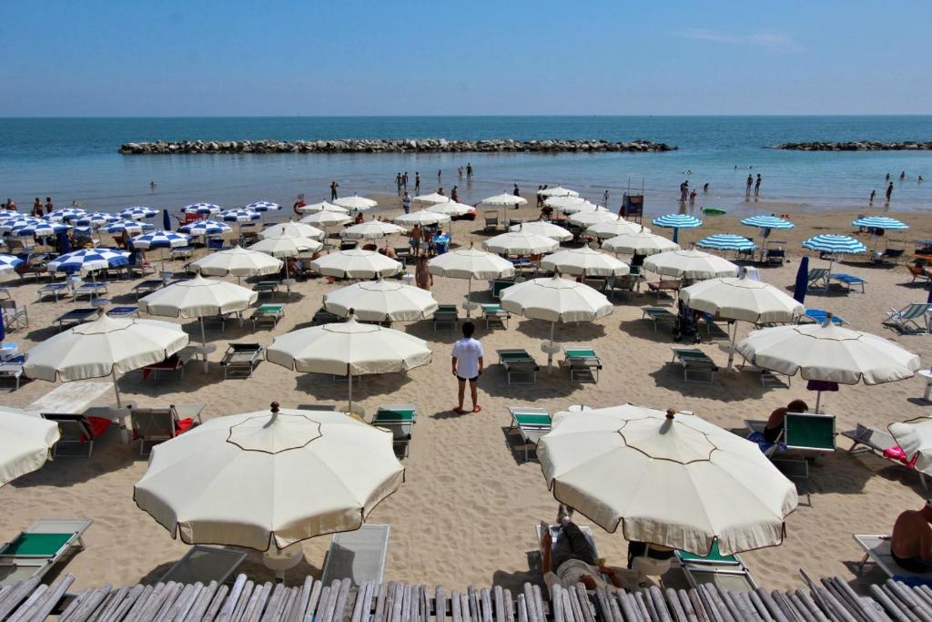 einen Strand mit vielen weißen Sonnenschirmen und Menschen darauf in der Unterkunft Residence Stella Marina in Cupra Marittima