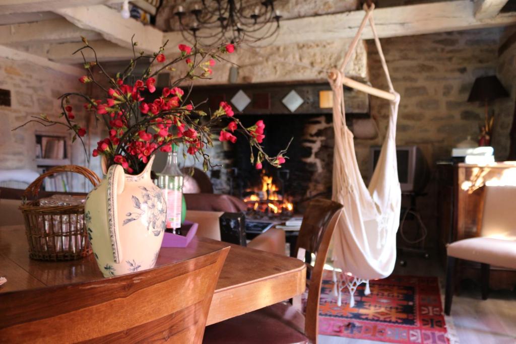 a dining room with a table with flowers and bags at Le Moulin à huile in Vailhourles