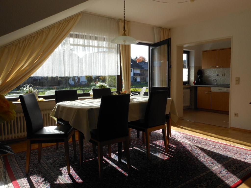 jadalnia ze stołem i krzesłami oraz dużym oknem w obiekcie Ferienwohnungen Westfalenhof w mieście Willingen