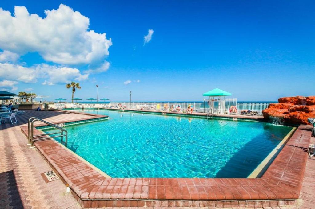 a swimming pool with the ocean in the background at Harbour Beach Resort Studios! in Daytona Beach