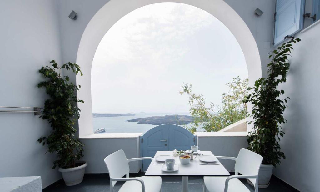 a dining room table with chairs and a large window at Kastro Suites in Fira