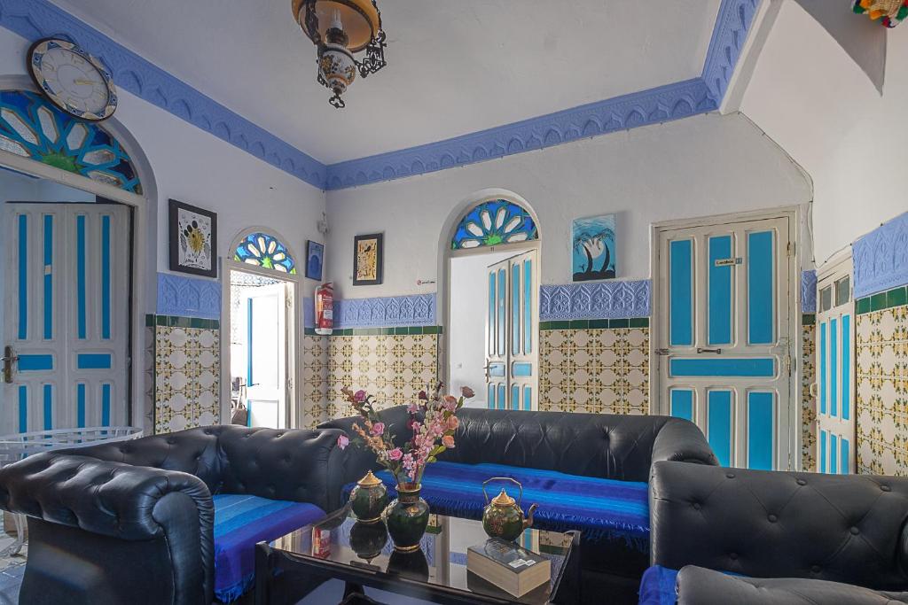 a living room with black leather furniture and blue walls at Hostal La Joya in Chefchaouene