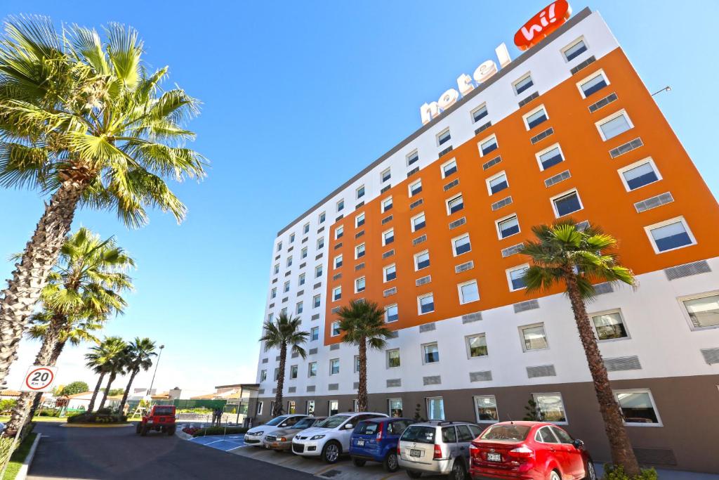 een hotel met palmbomen en auto's geparkeerd op een parkeerplaats bij Hotel Hi! Zapopan in Guadalajara