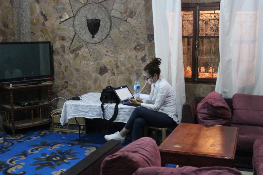 una mujer sentada en una mesa en una sala de estar en Riad Hiba, en Foum Zguid