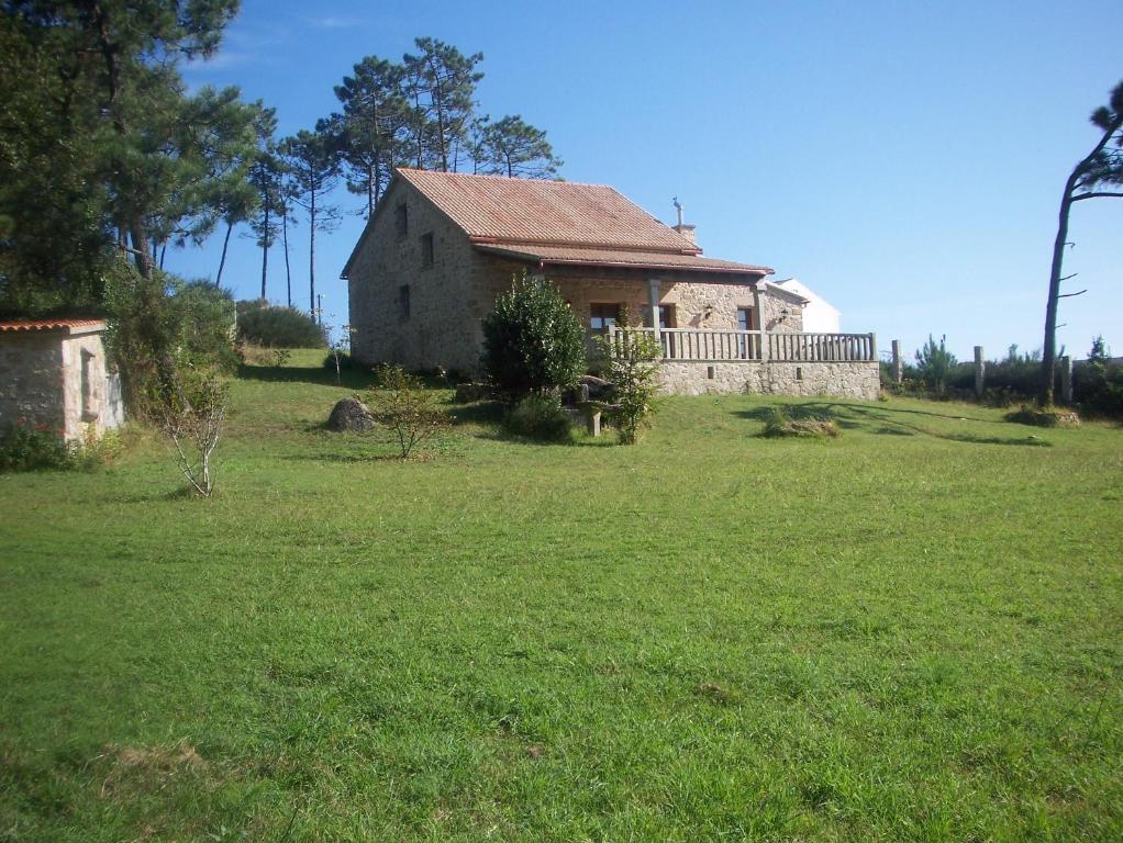 una casa vieja en un campo de césped verde en As Covas, en Ribeira