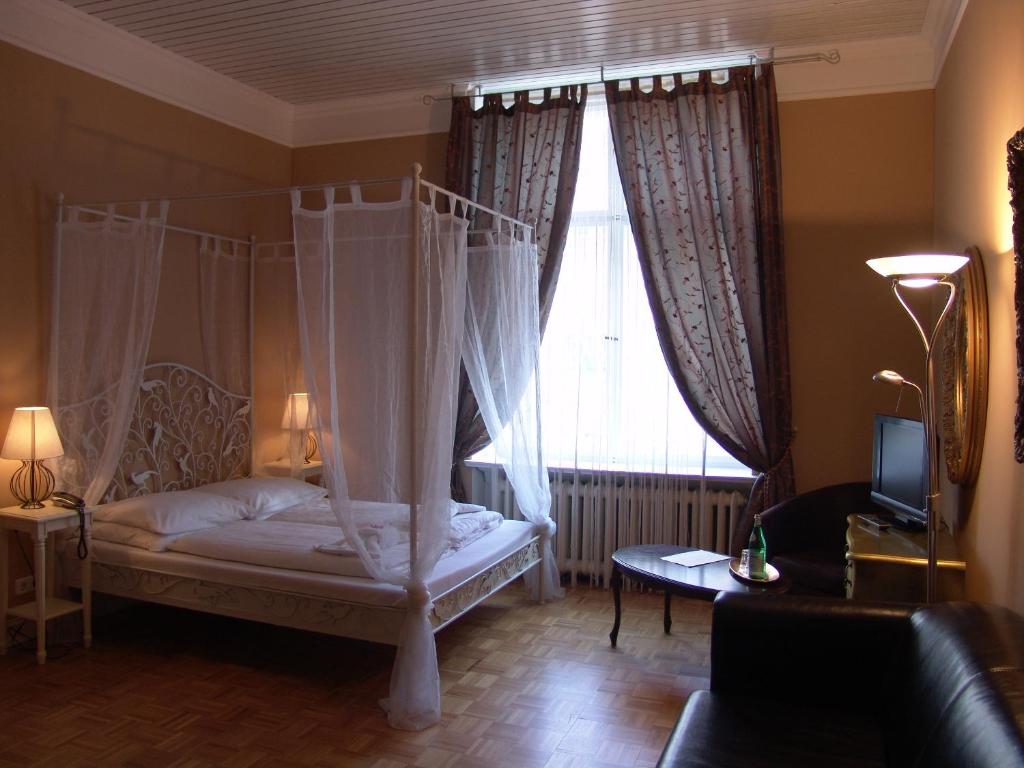 ein Schlafzimmer mit einem Himmelbett und einem Fenster in der Unterkunft Hotel-Maison Am Olivaer Platz in Berlin