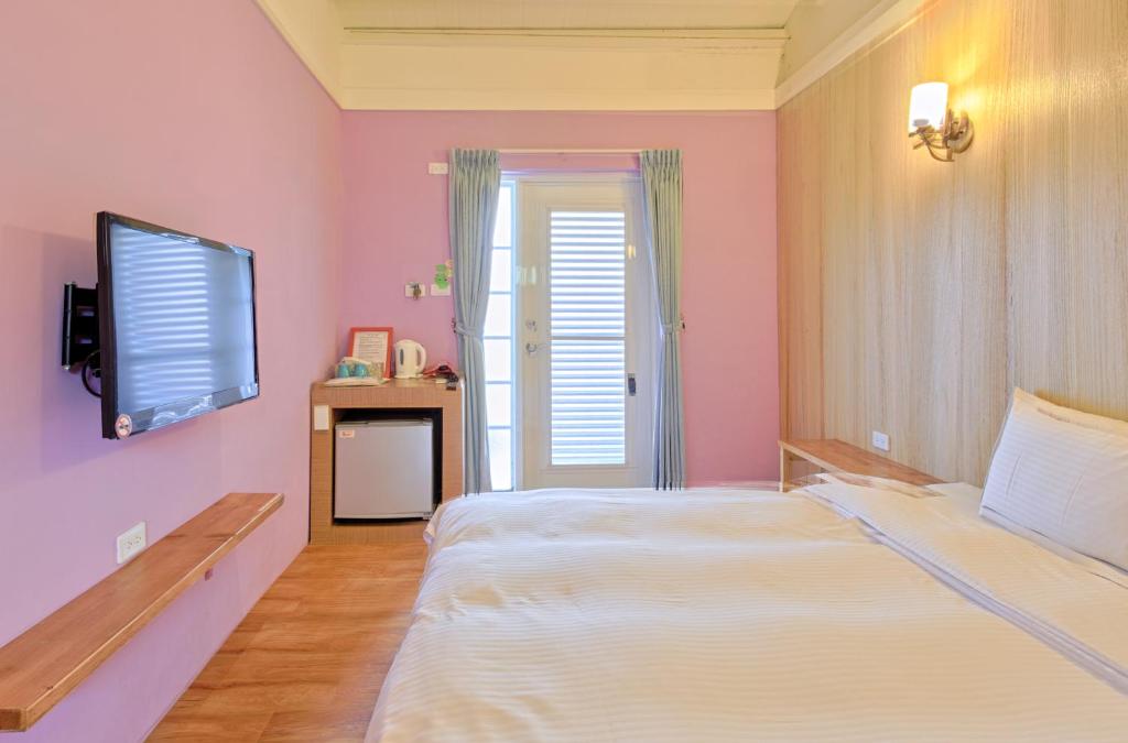 a bedroom with a bed and a flat screen tv at Love Summer Hostel in Hengchun South Gate