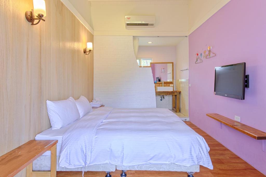 a bedroom with a white bed and a flat screen tv at Love Summer Hostel in Hengchun South Gate