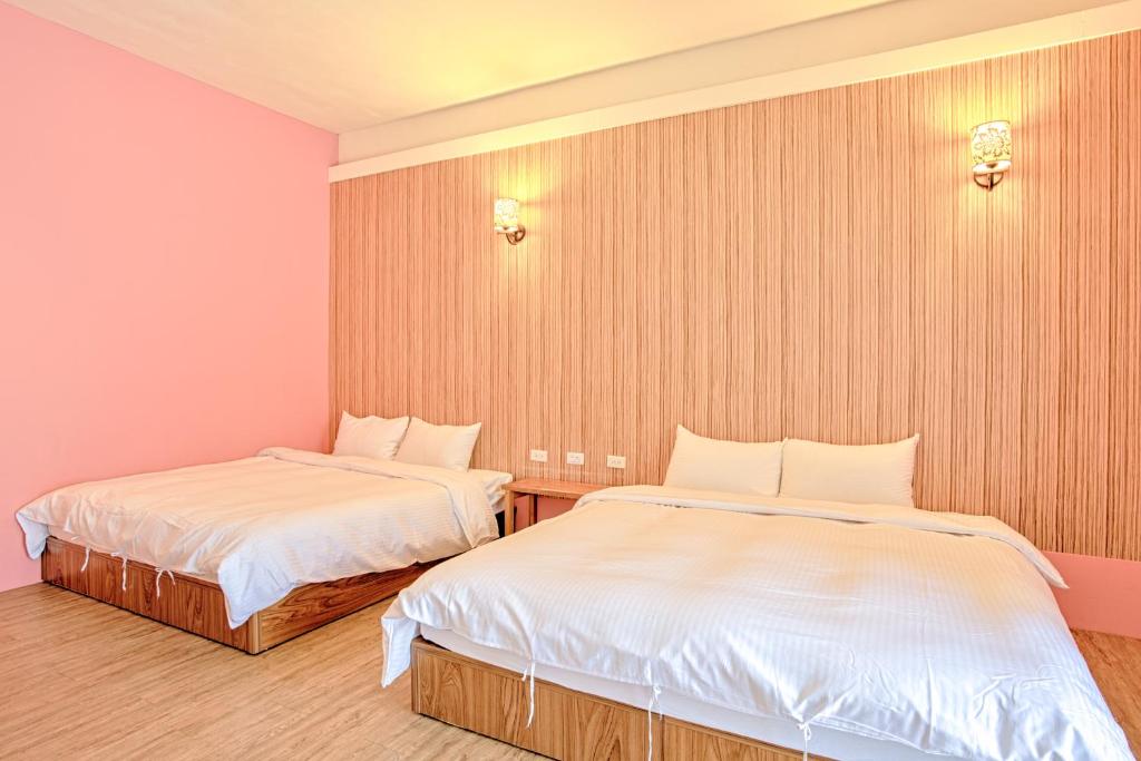two beds in a room with pink walls at Love Summer Hostel in Hengchun South Gate