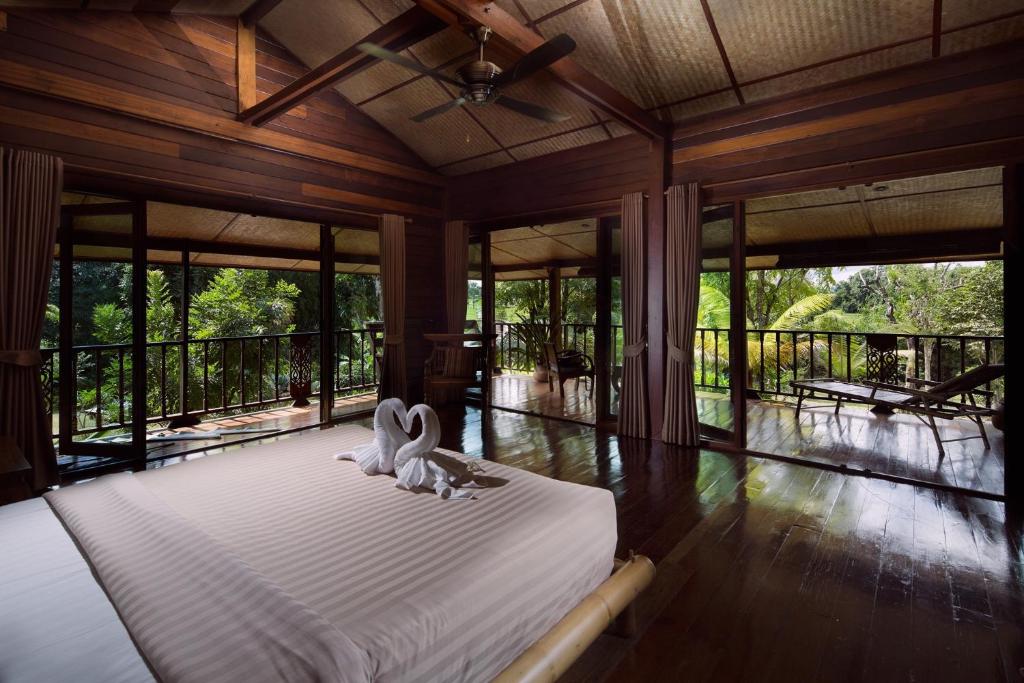 two white swans sitting on a bed in a room with windows at Bambuh Boutique Homestay in Ban Den