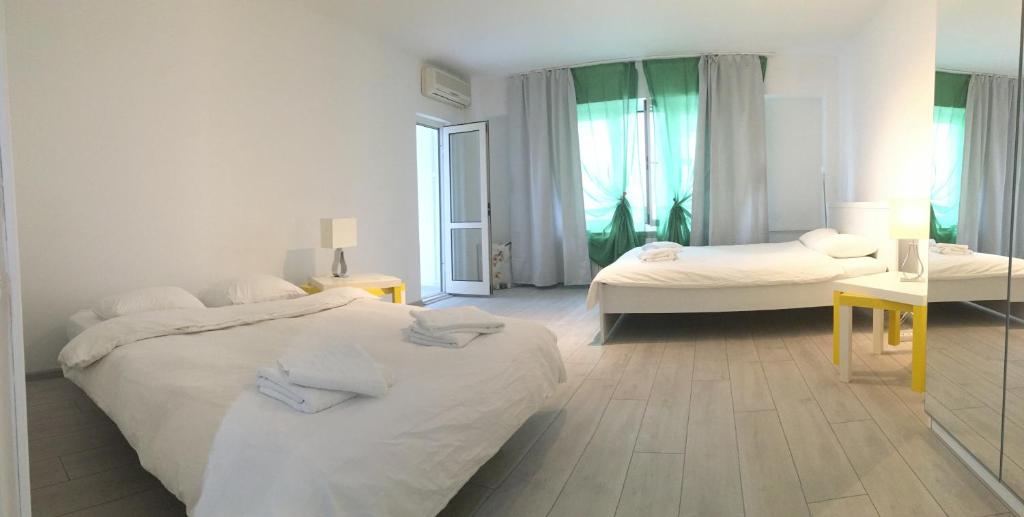 a white bedroom with two beds and a table at Green Apartment 4 Mircea Voda in Bucharest